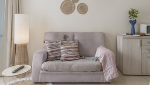 A modern living room with a sofa, a lamp, wall art, and a small table.