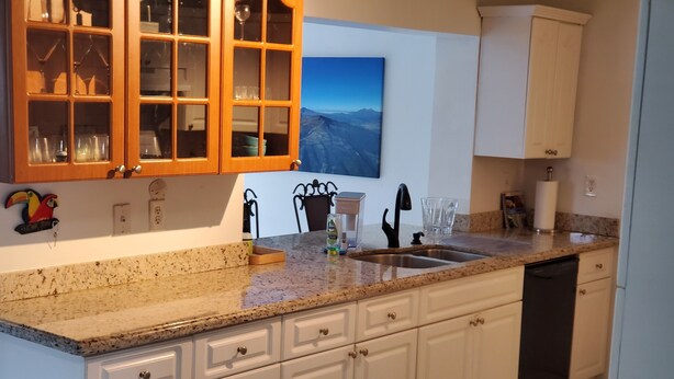 A kitchen with white cabinets, a granite countertop, a dishwasher, and a window with a mountain view. - Cozy family home in quiet area, nice garden views. (Miami)