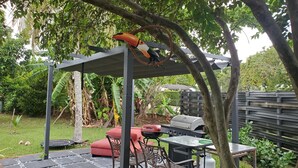 A covered outdoor seating area with a grill and a table. - Cozy family home in quiet area, nice garden views. (Miami)