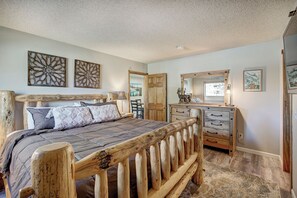 A bedroom with a wooden bed frame, a dresser, and a mirror. - Base 9 B101 (Breckenridge)