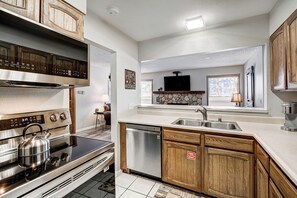 Una cocina moderna con electrodomésticos de acero inoxidable, armarios de madera, salpicadero de piedra y vistas al área de estar.
