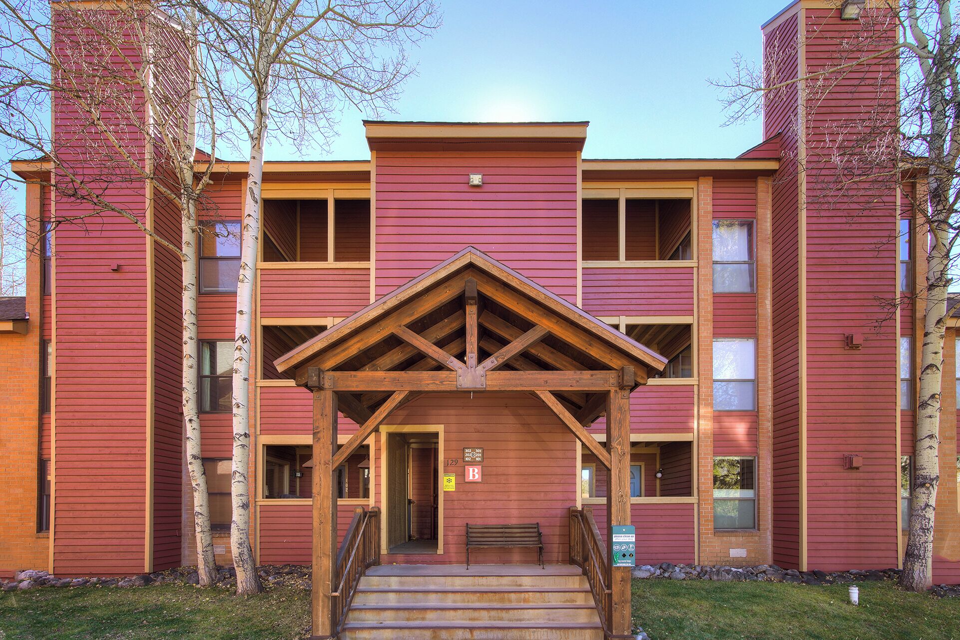 A multi-story building with a central entrance featuring a wooden porch and steps.