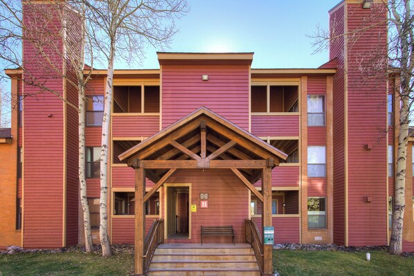 A multi-story building with a central entrance featuring a wooden porch and steps. - Base 9 B101 (Breckenridge)