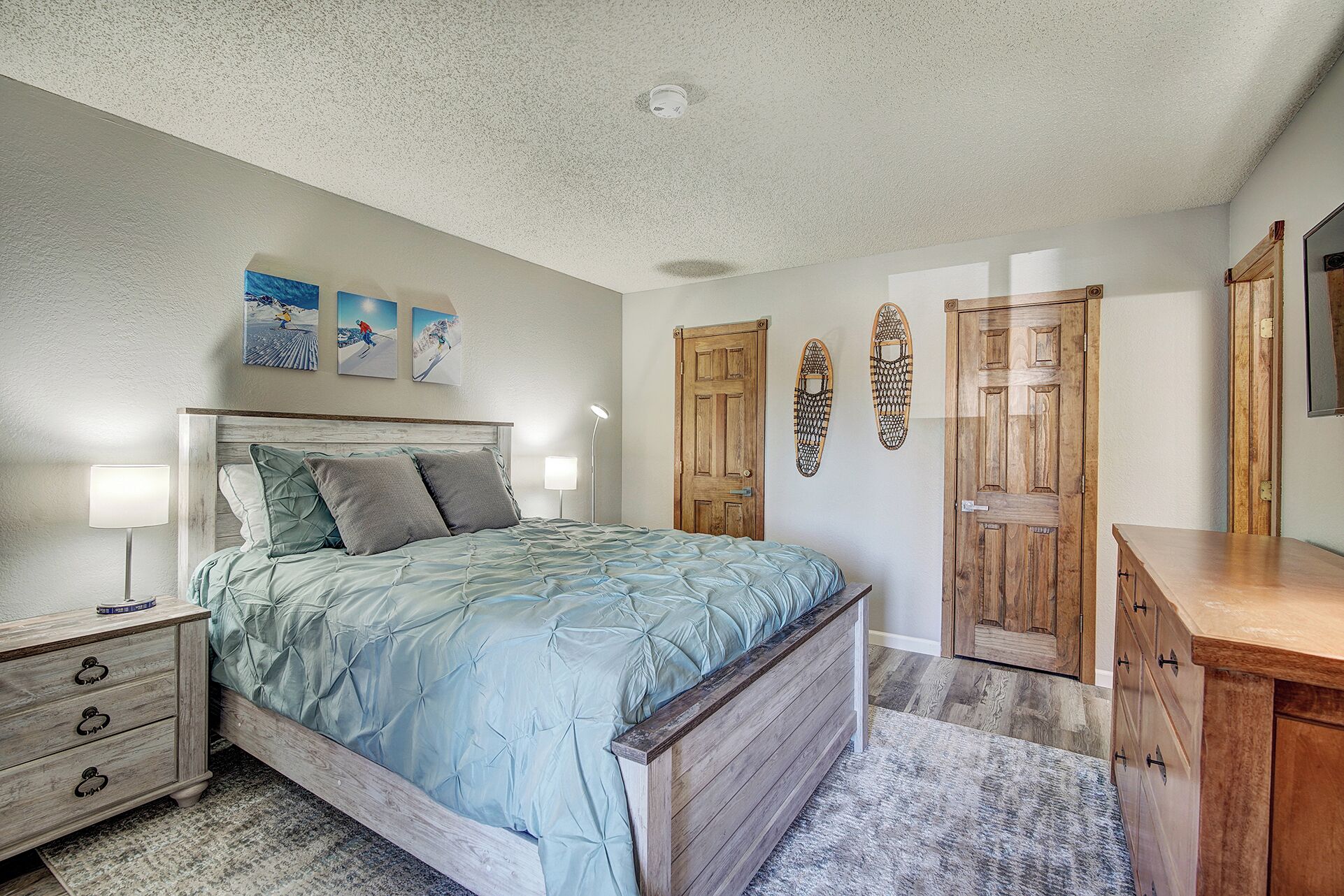 Une chambre à coucher avec un lit, des tables de chevet, une commode et un luminaire au plafond.
