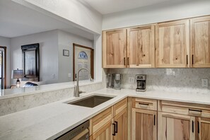 A kitchen with wooden cabinets, a sink, and a coffee maker. - Base 9 B101 (Breckenridge)