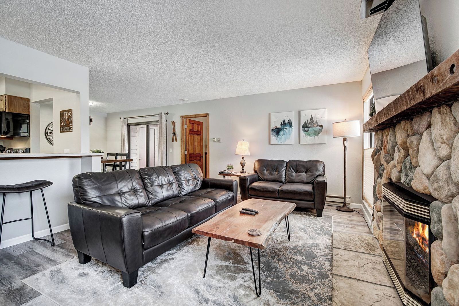 A living room with a fireplace, a sofa, a coffee table, and a stone wall.