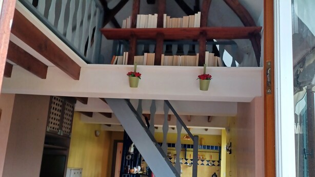 Une pièce avec un escalier, un coin repas et une cuisine à l’arrière-plan.