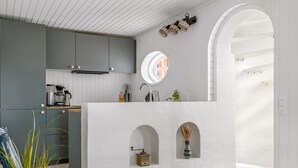 Une cuisine moderne avec un îlot central blanc, des armoires grises et une fenêtre ronde.