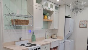 A kitchen with white cabinets, a stove, a sink, and a washing machine.