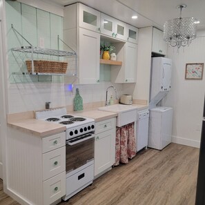 Kitchen features a gas stove, white oven, and sink with faucet, along with ample storage in white cabinets.