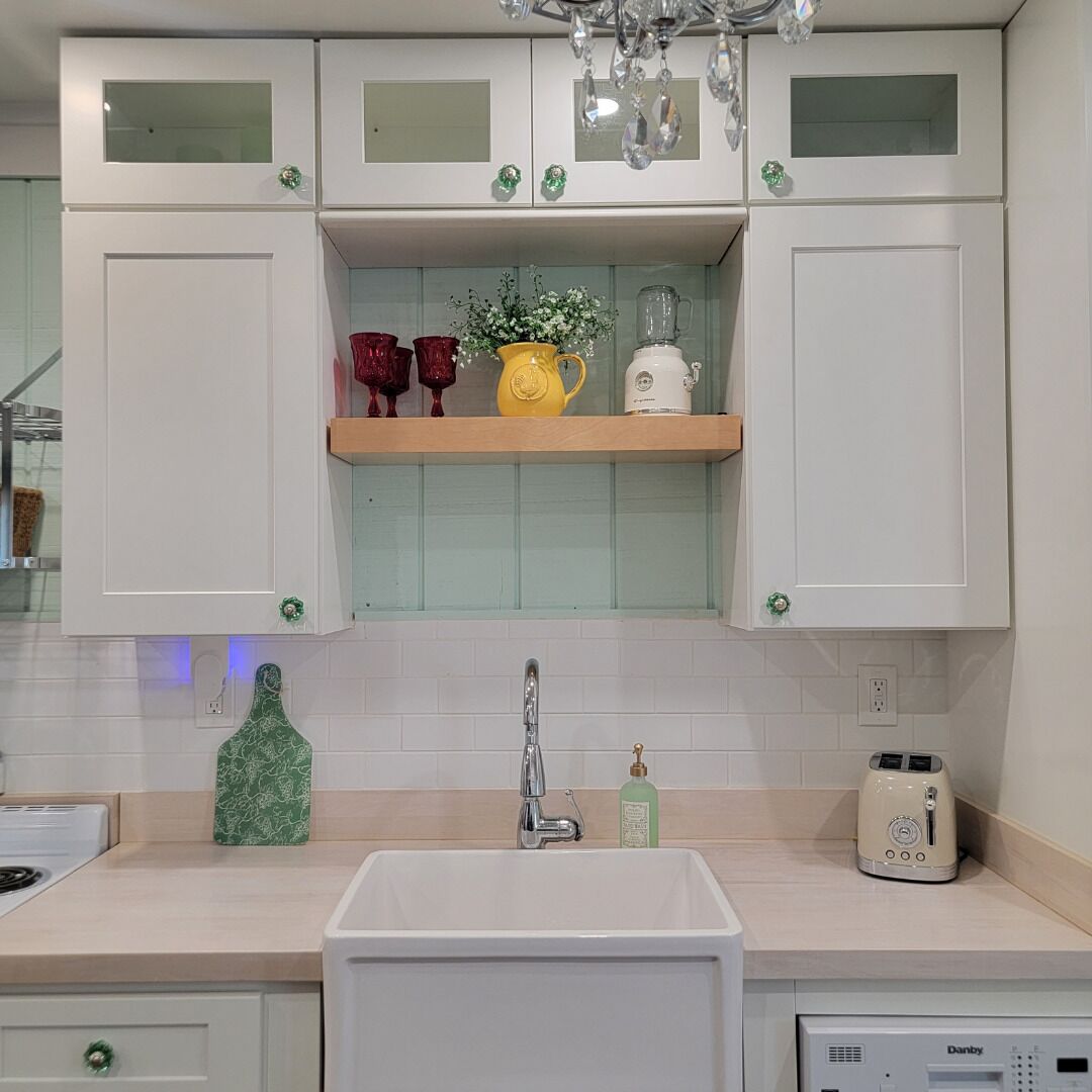 A kitchen with white cabinets, a sink, a toaster, and a green bottle on the counter.