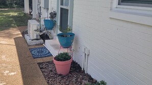A house with a covered porch, potted plants, and a small garden area with mulch.