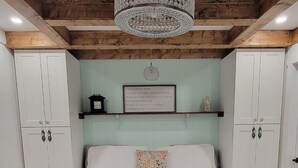 A bedroom with a bed, a chandelier, a wall-mounted clock, and a motivational quote.