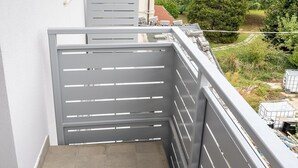 A balcony with a grey metal railing, a view of a garden, and a building in the background. - SE029 - Mondolfo, new three-room apartment with balcony and air conditioning (Mondolfo)