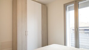 A bedroom with a bed, a wardrobe, and a sliding glass door to the outside. - SE029 - Mondolfo, new three-room apartment with balcony and air conditioning (Mondolfo)