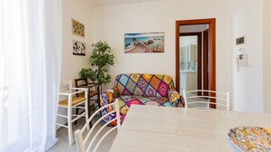 Una zona de menjador amb una taula, cadires, un sofà i un quadre a la paret.