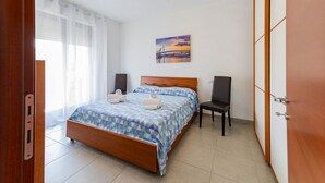 Un dormitori amb llit, cadira, quadre i armari.