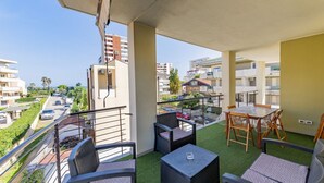Un balcó amb mobles d'exterior, vista del carrer i edificis al fons.