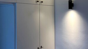 Une pièce avec une armoire blanche, un luminaire fixé au mur et une porte.