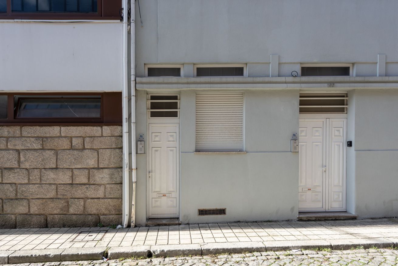 A building with a white facade, a brick lower section, and two white doors with shutters.