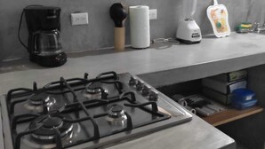 Une cuisine équipée d’une cuisinière à gaz, d’une machine à café, d’un mixeur et d’un rouleau d’essuie-tout.