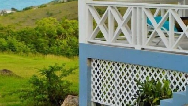 A covered outdoor area with a view of the ocean and hills.