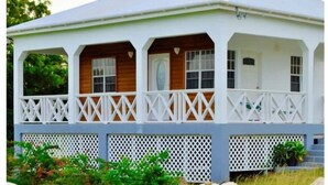 A white, single-story building with a porch and lattice railings.