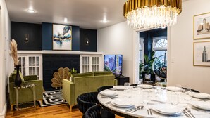 A dining area with a round table set for six, a green sofa, and a fireplace. - Spacious! Game Room, near Restaurants, Bars, Shops, DT BFLO & Niagara Falls! (Buffalo)