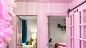 A hallway with pink doors leading to a bedroom with a bed and a nightstand. - Spacious! Game Room, near Restaurants, Bars, Shops, DT BFLO & Niagara Falls! (Buffalo)