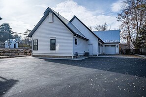 Ein zweistöckiges weißes Gebäude mit einem Giebeldach, einer Garage und einer Steinsäule im Hintergrund.