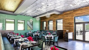 A modern restaurant with green walls, wooden accents, and a variety of seating options including tables and booths.