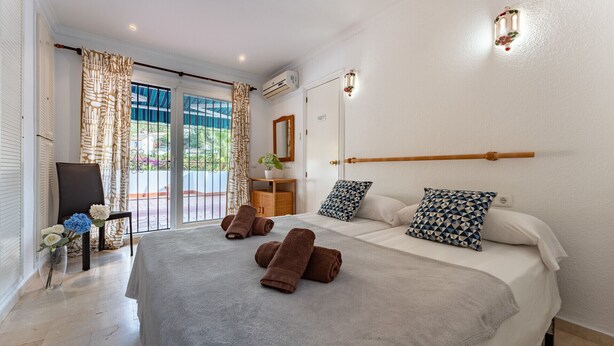 A hotel room with a large bed, two bedside tables, a mirror, and a view of the outdoors. - MalagaSuite Blue Paradise House (Benalmádena)