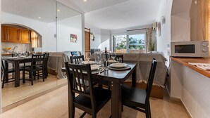 A modern kitchen with a dining area, a large window with a view, and a microwave on the counter. - MalagaSuite Blue Paradise House (Benalmádena)