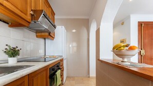 A kitchen with wooden cabinets, a built-in stove, and a bowl of fruit on the counter. - MalagaSuite Blue Paradise House (Benalmádena)