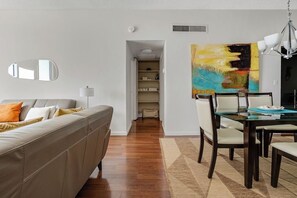 Ein modernes Wohnzimmer mit einer Couch, einem Esstisch, Stühlen und einem Gemälde an der Wand.