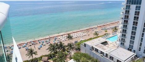 A hotel with a pool, beach view, and a high-rise building.
