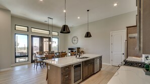 A spacious kitchen with a large island, stainless steel appliances, and pendant lighting. - 7 Mi to Lost Dutchman: Home w/ Pool + Patio! (Apache Junction)