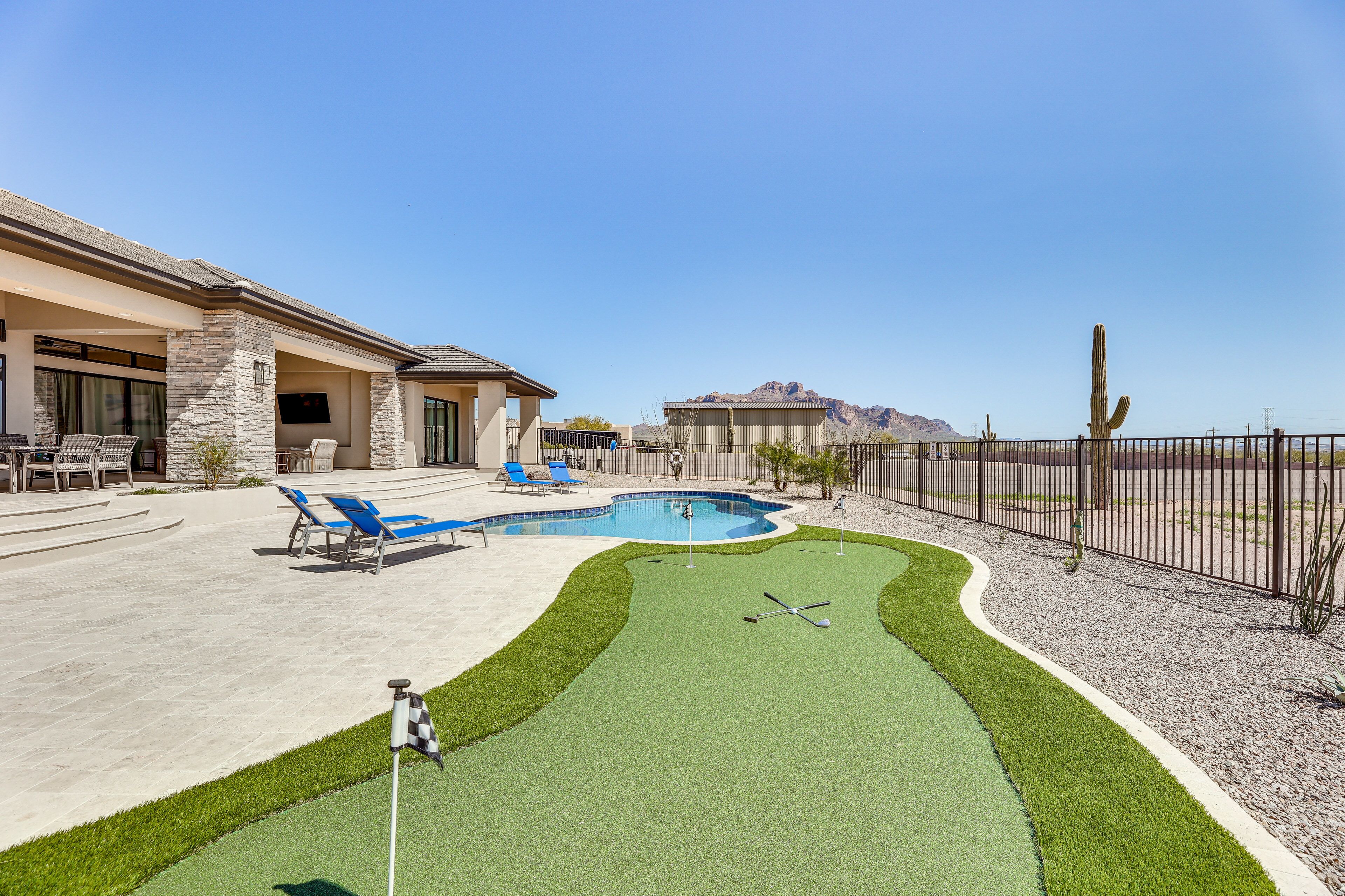 Un cortile con piscina, campo da golf in miniatura e un cactus.