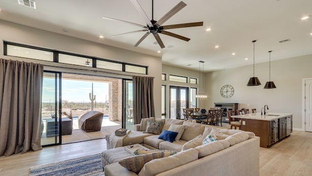 A spacious living room with a large sectional sofa, a ceiling fan, and a sliding glass door leading to a patio. - 7 Mi to Lost Dutchman: Home w/ Pool + Patio! (Apache Junction)