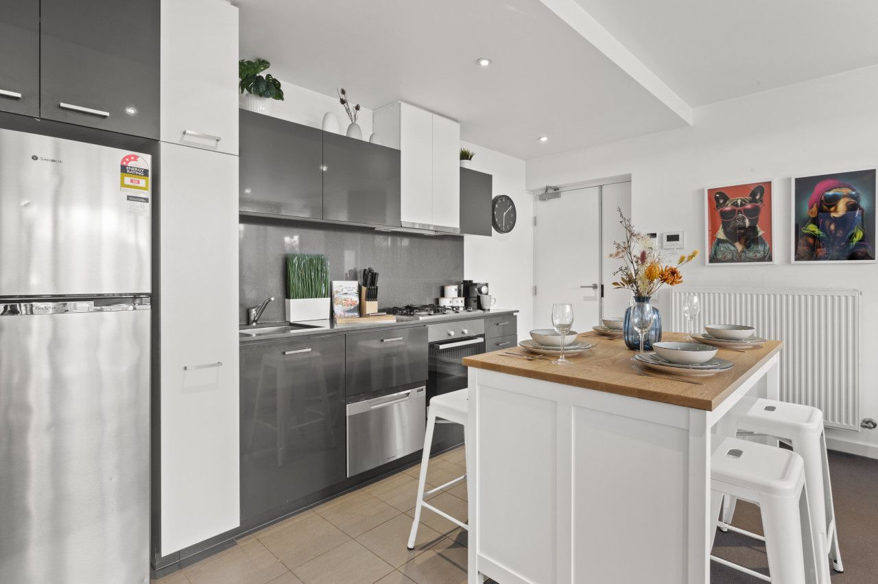 Een moderne keuken met roestvrijstalen apparatuur, witte kasten en een centraal eiland met krukken.