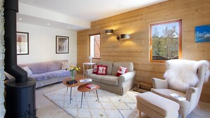 A cozy living room with a sofa, armchair, and a fireplace.