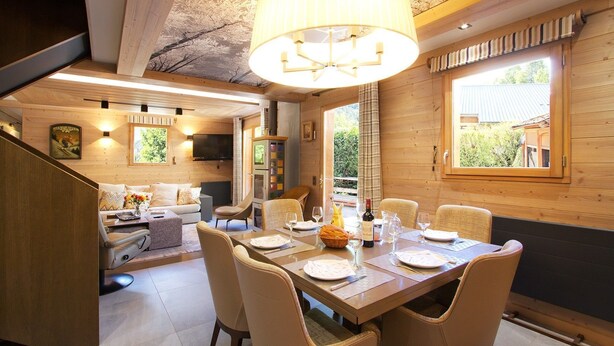 A cozy wooden interior with a dining area, a sofa, and a TV.