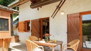 A wooden deck with a table and chairs, a wooden door, and a window.