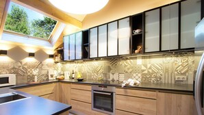 A modern kitchen with wooden cabinets, a built-in oven, and a skylight.