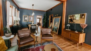 Una sala de estar acogedora con sillones de cuero, una mesa de centro de madera y un cuadro grande en la pared.