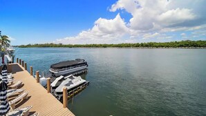 A docked boat with a covered deck, lounge chairs, and a clear view of the water and distant shoreline. - Waterside Escape w/Queen Bed and Free Parking (Hollywood)