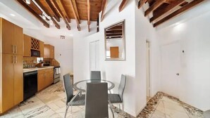 A dining area with a round table and four chairs, a kitchen with wooden cabinets, and a tiled floor. - Waterside Escape w/Queen Bed and Free Parking (Hollywood)
