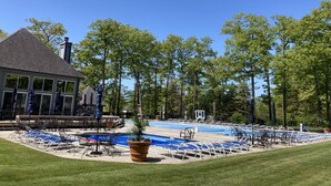 A pool area with lounge chairs and umbrellas, surrounded by trees and a building with large windows. - Pool Access | Fireplace, Deck & A/C (Somerset)