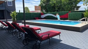 A swimming pool with red lounge chairs and a waterfall feature. - Queen's Two Bedroom apartment with Pool View (Welgelegen)