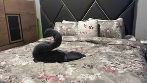 A bed with a floral bedspread and a black swan decoration. - Queen's Two Bedroom apartment with Pool View (Welgelegen)